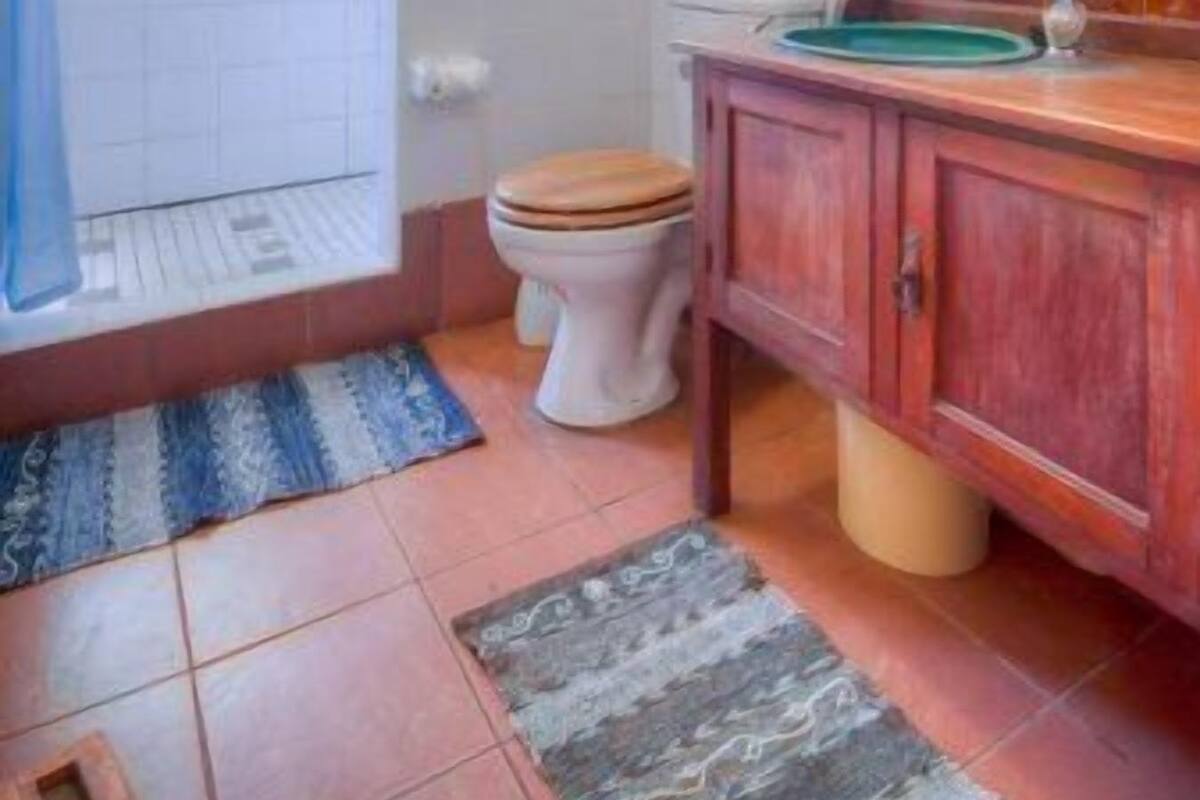 A bathroom with a toilet, sink, and a window.