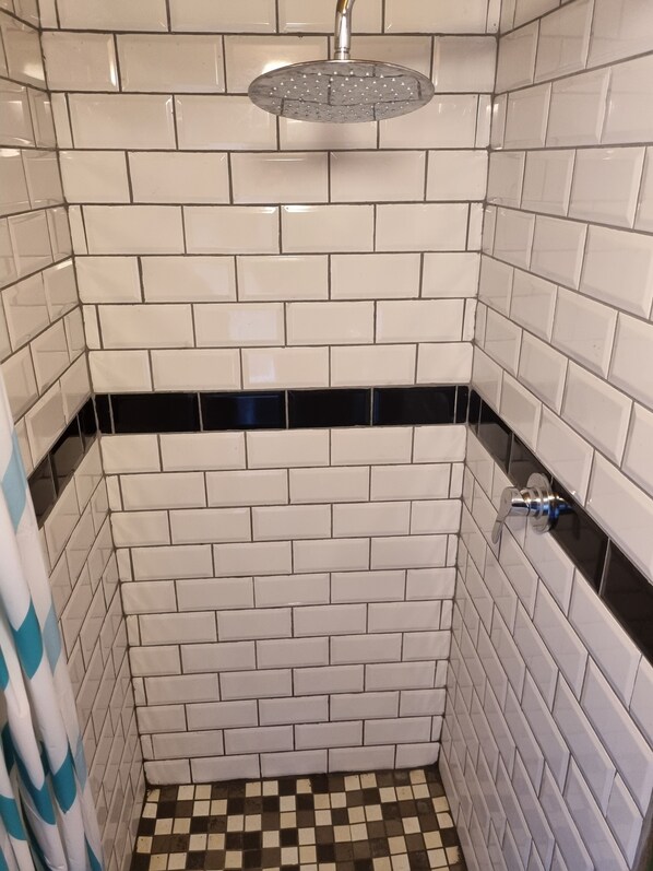 A bathroom with white subway tiles, a black and white checkered floor, and a showerhead.