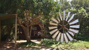 Un molino de madera rústico y una estructura de madera con techo en un jardín.