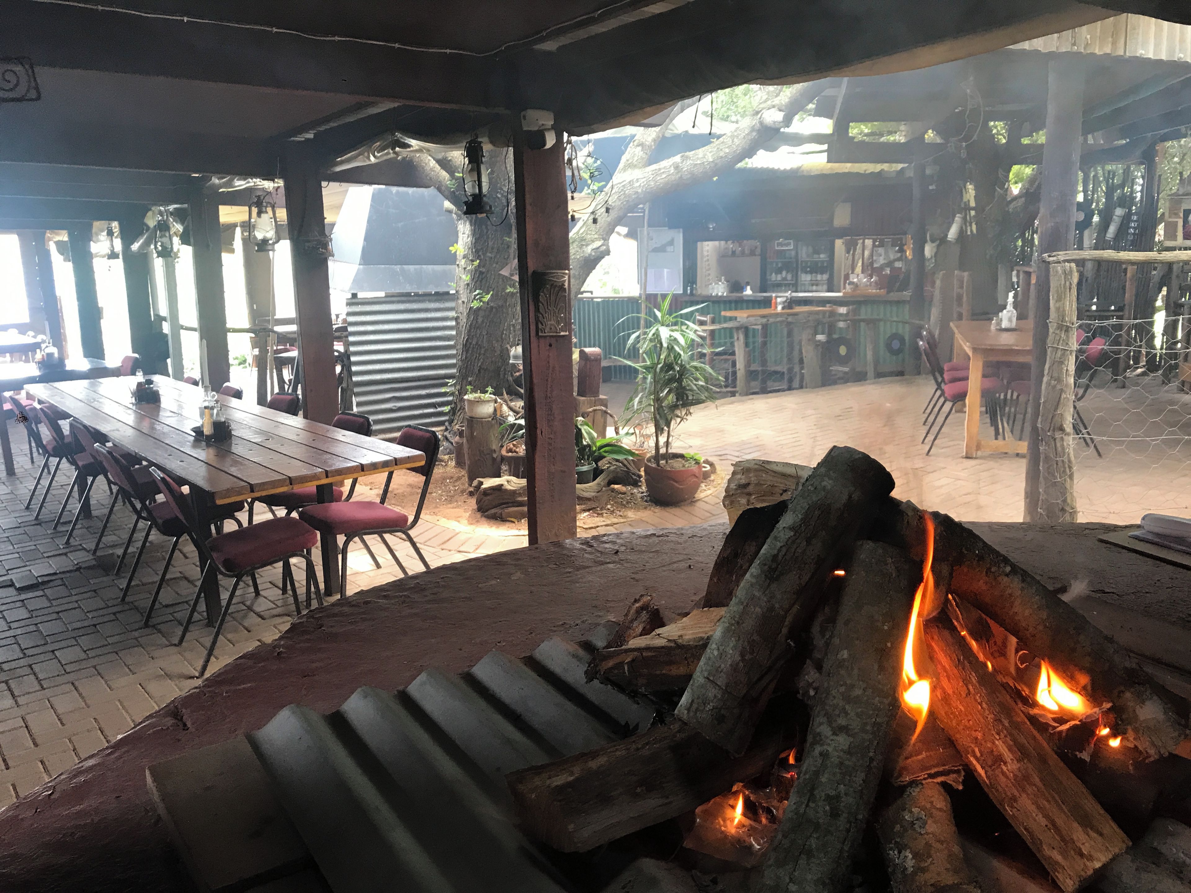 An outdoor dining area with a fire pit, tables, and chairs.