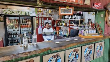 A bar with a goat-themed logo, a Coca-Cola sign, and a variety of liquor bottles.