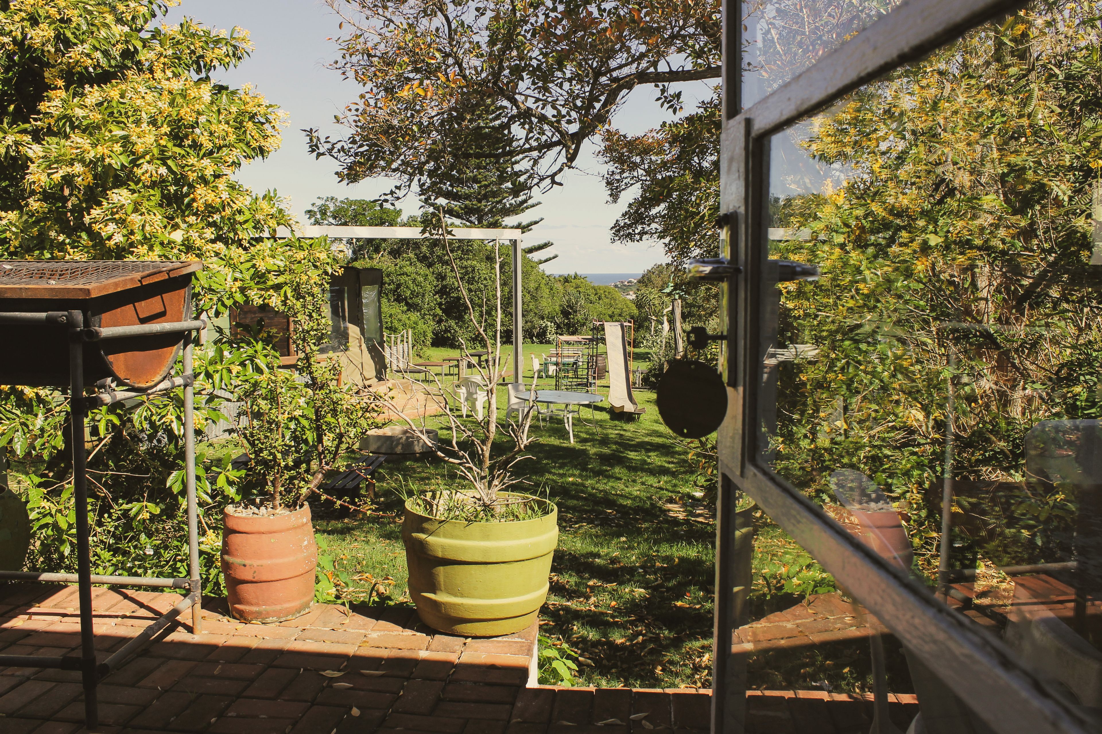 Ein Garten mit Blumentöpfen, einer Pergola und Blick auf das Meer.