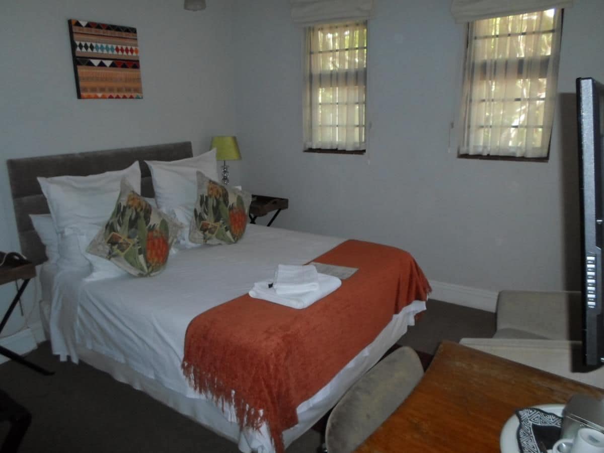 A hotel room with a bed, a TV, a desk, and a window.