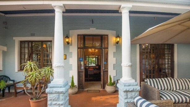A covered outdoor area with a seating arrangement and potted plants. - Melville Turret Guesthouse (Johannesburg)