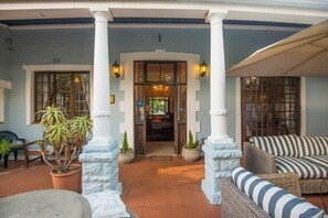 A covered outdoor area with a seating arrangement and potted plants. - Melville Turret Guesthouse (Johannesburg)