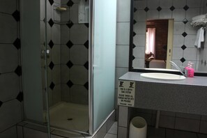 A bathroom with a glass-enclosed shower, a sink with a mirror, and a sign instructing to throw all foreign matter into a bin. - Jabula Lodge (Nkomazi)