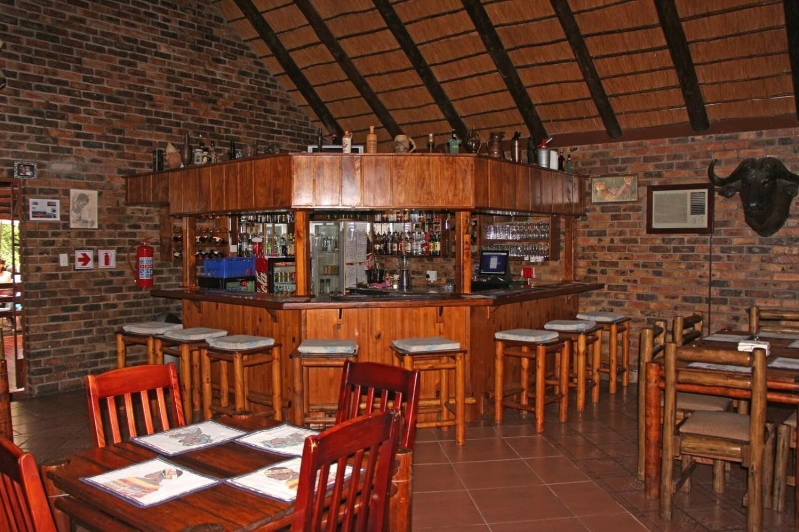 Un espace bar avec des tabourets en bois, un comptoir et un mur en briques.