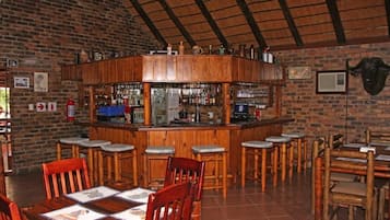 Un espace bar avec des tabourets en bois, un comptoir et un mur en briques.