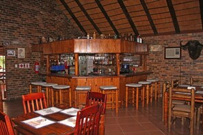A bar area with wooden stools, a counter, and a brick wall.