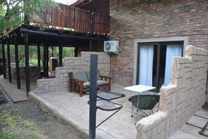 A patio area with a stone bench, a table, and a chair.