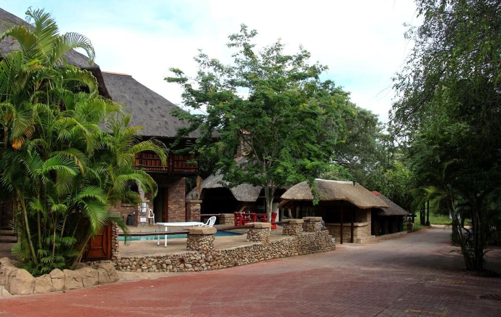 A resort with a pool, thatched-roof structures, and lush greenery.