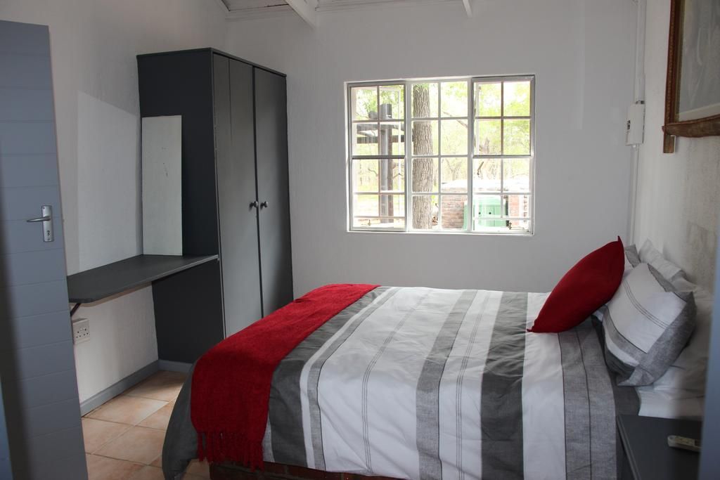 A bedroom with a bed, a window, a wardrobe, and a door.