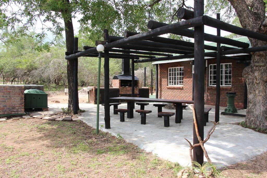 Een terras buiten met picknicktafels en een gebouw van baksteen.