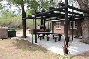 An outdoor patio area with picnic tables and a brick building. - Jabula Lodge (Nkomazi)