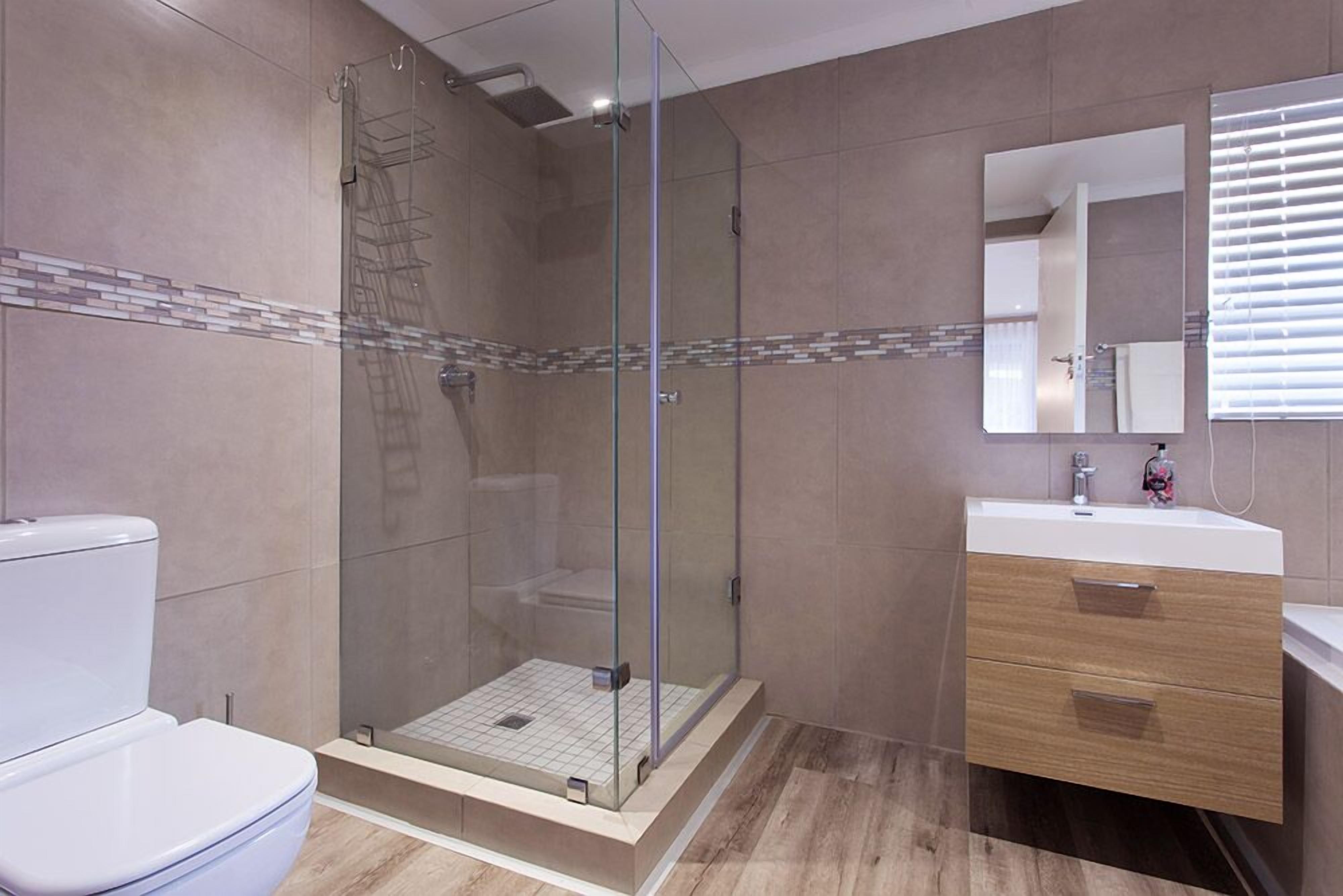 A modern bathroom with a glass-enclosed shower, a toilet, and a vanity with a mirror.