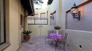 A patio area with a table and chairs, a potted plant, and a wall-mounted light fixture.