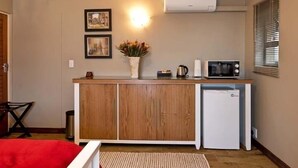 A compact kitchen with a wooden cabinet, a small refrigerator, a microwave, and a sink.