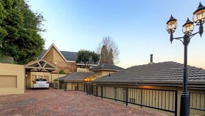 A residential driveway with a paved surface, a white car parked, and a black metal fence.