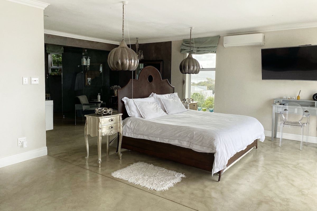 A bedroom with a large bed, a desk, and a TV.