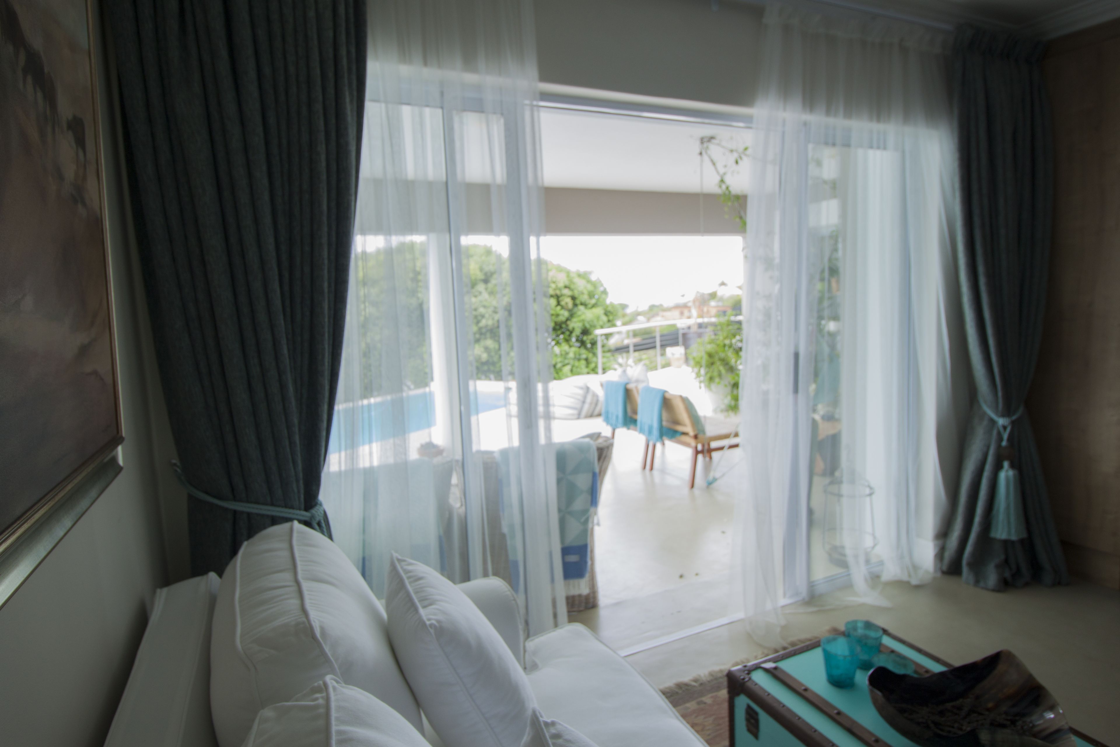 Et værelse med sofa, et bord med en vase og udsigt til en balkon med stol og bord.