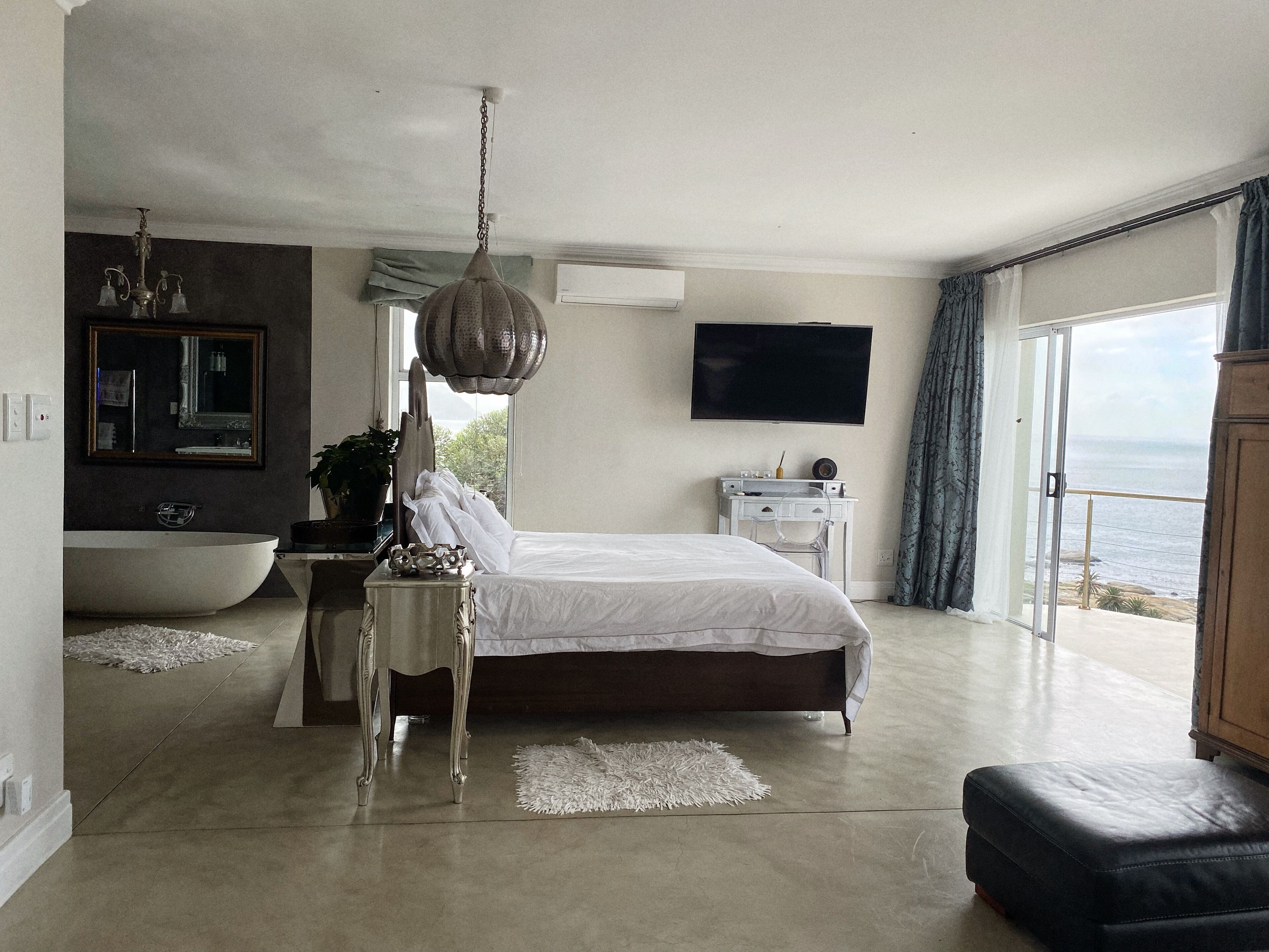 Une chambre avec un grand lit, une baignoire, un bureau, une télévision et une vue sur la mer.