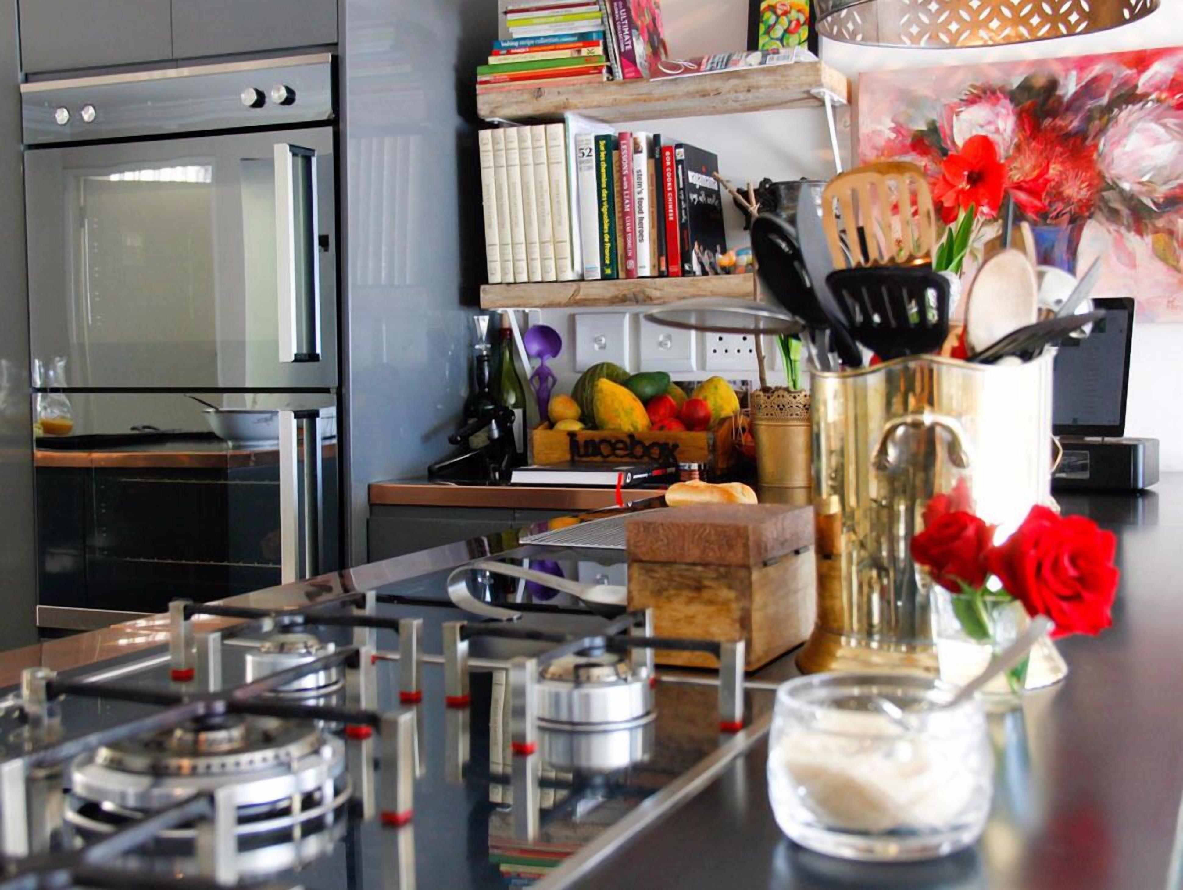 A kitchen with a gas stove, oven, and a variety of kitchen items on the counter.