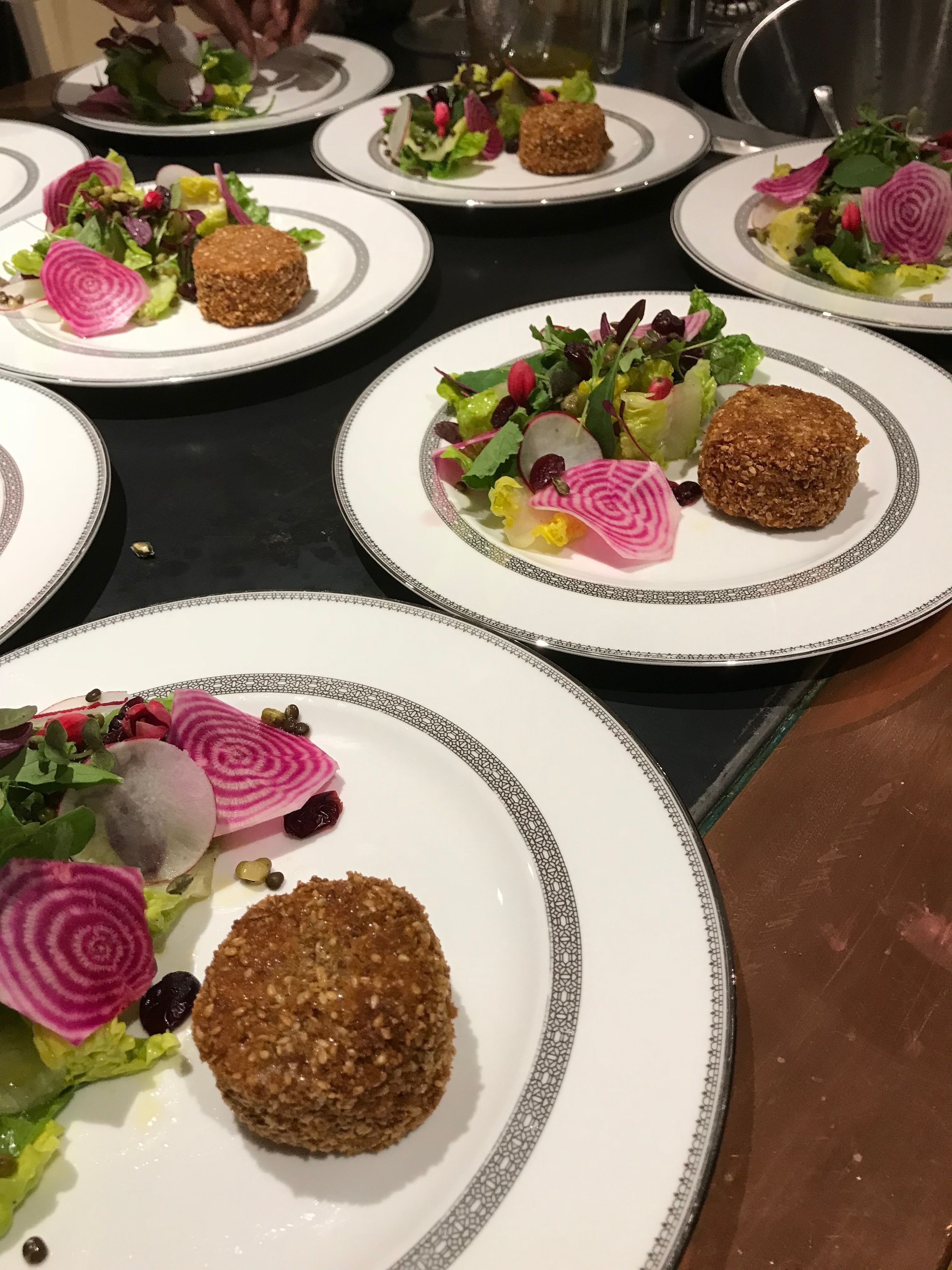 Una mesa de comedor con varios platos de comida, cada uno con un elemento circular central y diversas guarniciones.