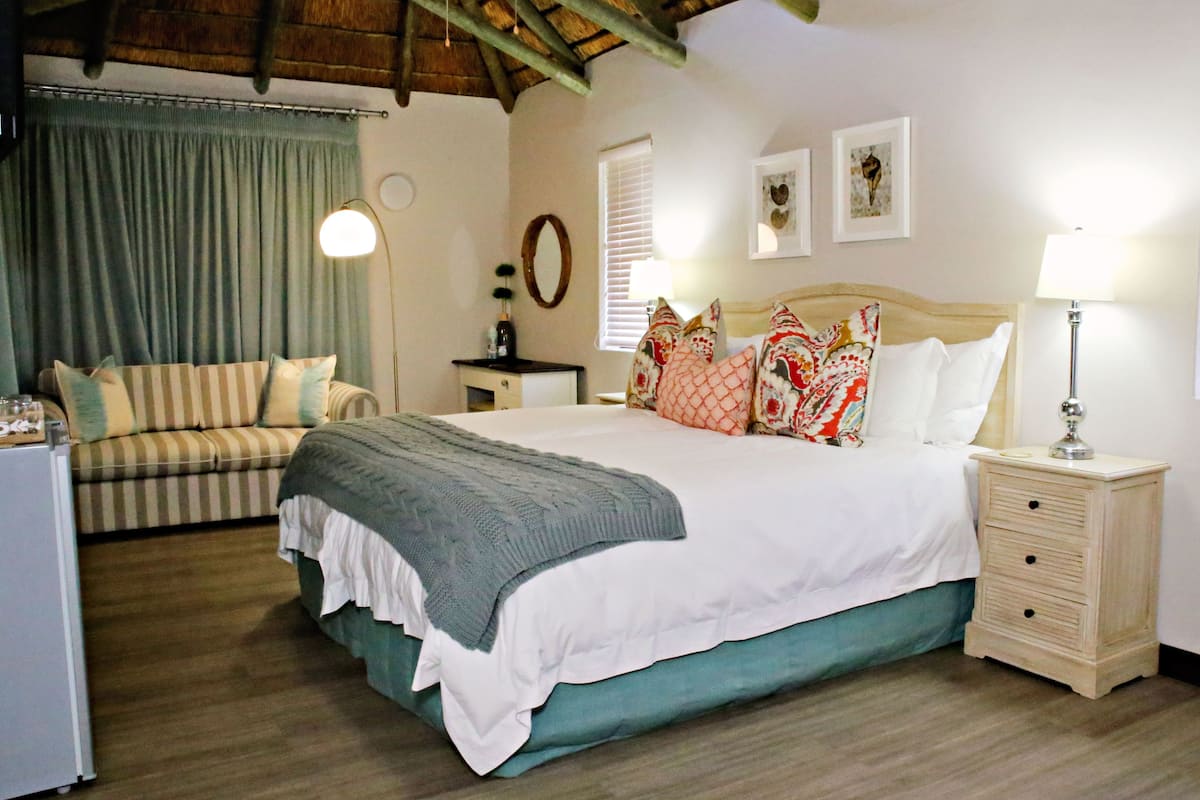 Une chambre à coucher avec un lit, une table de chevet, une lampe et un canapé.