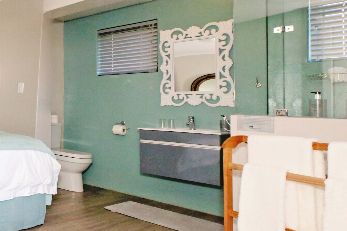 Une chambre à coucher comprenant un lit, des tables de chevet, des toilettes, un lavabo et un miroir.