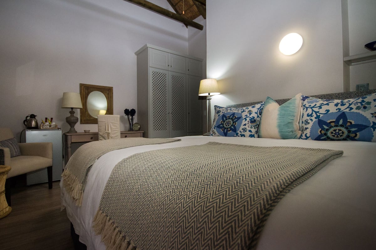 Une chambre à coucher comprenant un lit, une table de chevet, une lampe, une armoire et une chaise.