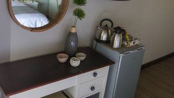 A small room with a wooden desk, a mirror, a television, and a refrigerator.