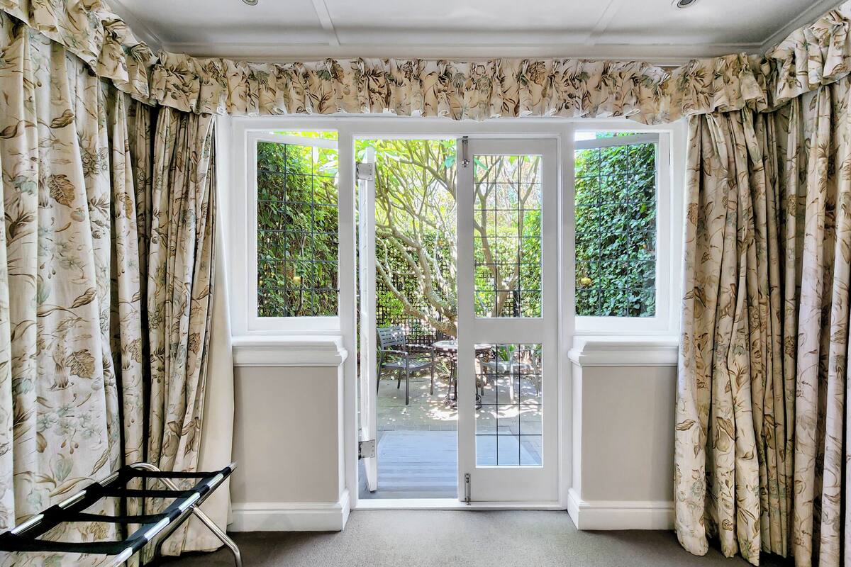 A room with a large glass door leading to an outdoor area with greenery.