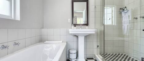 A modern bathroom with a bathtub, a pedestal sink, and a glass shower enclosure.