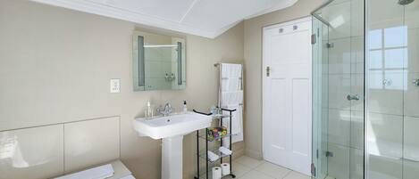 A modern bathroom with a skylight, a glass shower enclosure, and a white sink.
