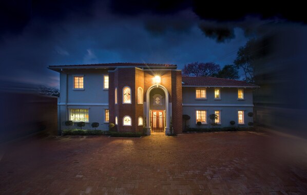 A two-story house with a brick facade, a central entrance with a glass door, and multiple windows.