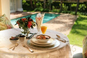 A table set for breakfast with a bowl of cereal, a glass of orange juice, and a vase of flowers.