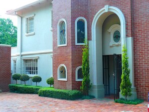 A two-story building with a brick facade, multiple arched windows, and a gated entrance.