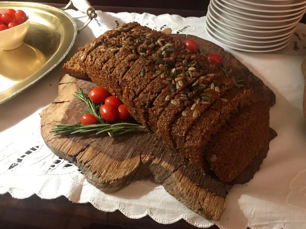 A loaf of bread on a wooden board with cherry tomatoes and rosemary.