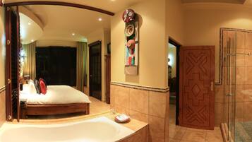 A spacious bathroom with a large bathtub, a glass shower enclosure, and a vanity with a red bowl sink.