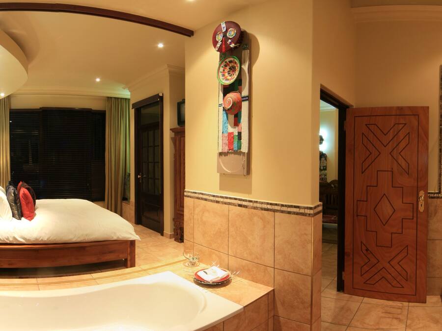 A spacious bathroom with a large bathtub, a glass shower enclosure, and a vanity with a red bowl sink.
