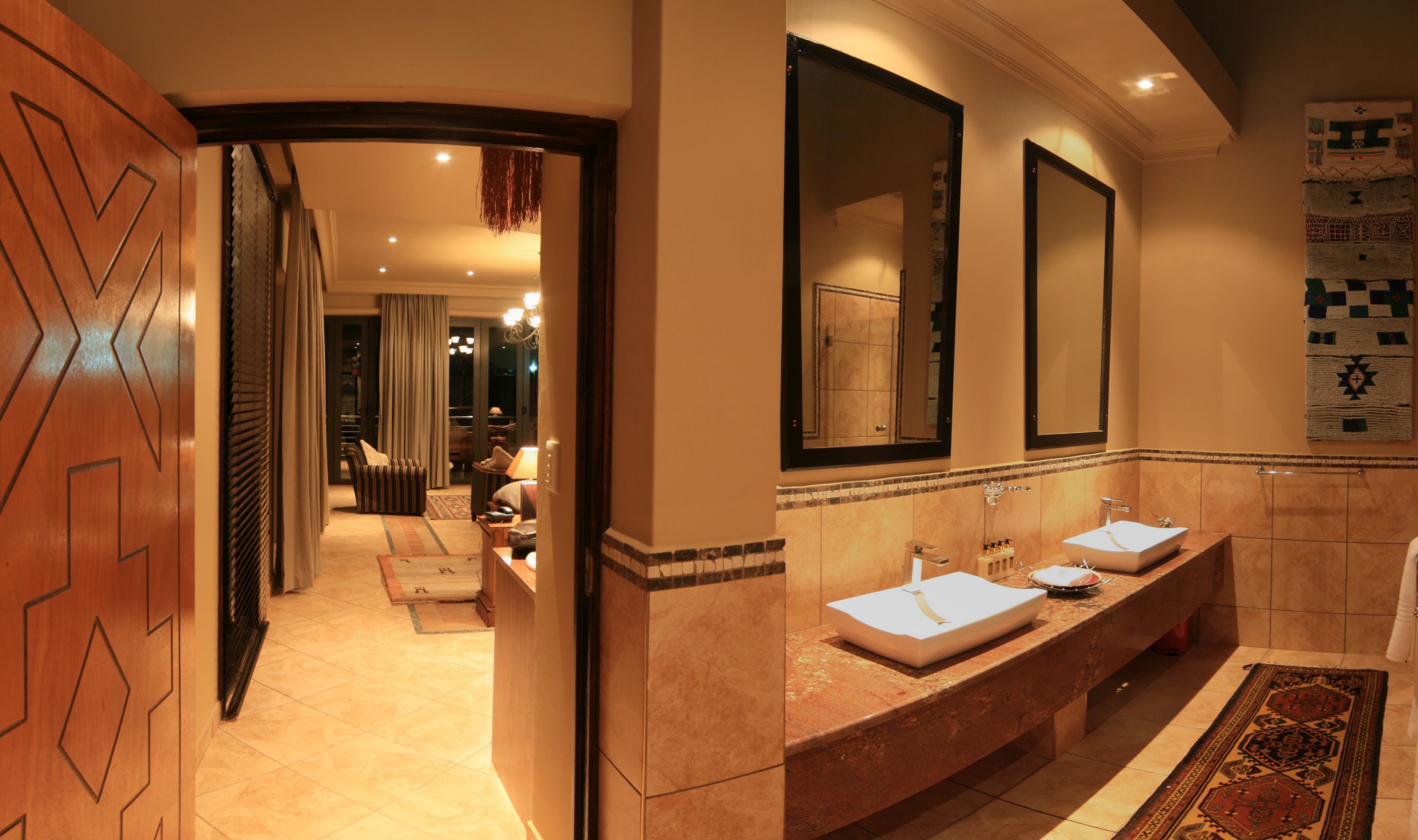 A hotel bathroom with two sinks, a large mirror, and a shower area.