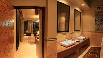 A hotel bathroom with two sinks, a large mirror, and a shower area.