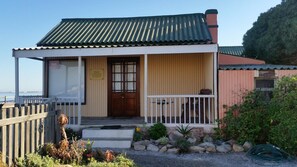 A small, single-story building with a green metal roof and a wooden door. - Bedrock Lodge (Port Nolloth)