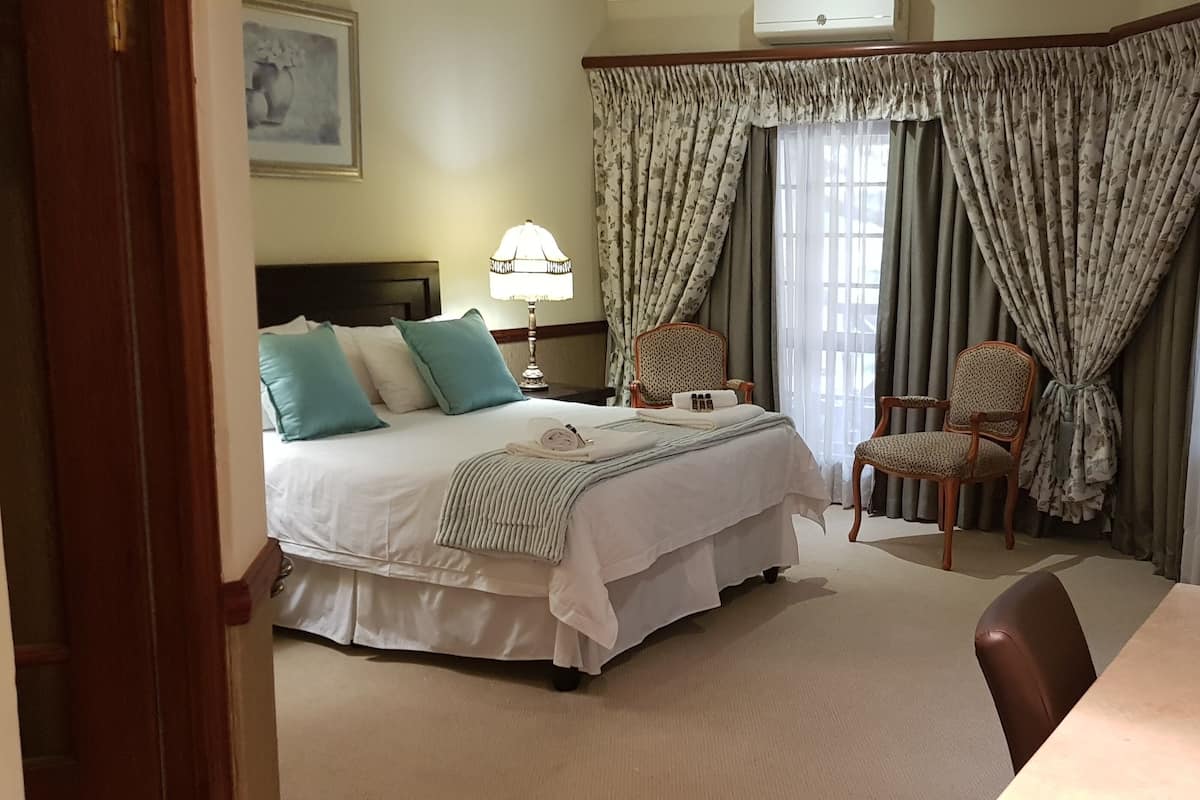 A hotel room with a bed, two chairs, a table, and curtains.