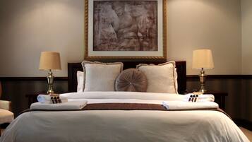 A hotel room with a large bed, two bedside lamps, a framed artwork above the bed, and a wooden headboard.