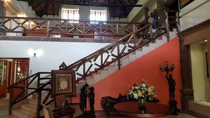 A spacious lobby with a grand staircase, a chandelier, and a large framed picture. - Prinshof Manor Guesthouse (Pretoria)