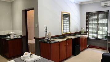 Habitación de hotel con cama, baño con lavabo y espejo, y ventana con persianas.