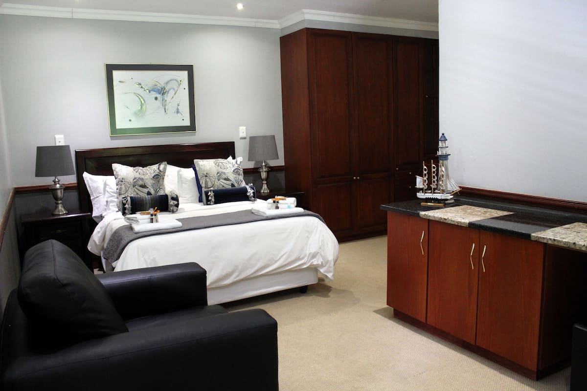 A hotel room with a bed, bedside tables, a desk, and a wardrobe.