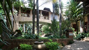 A courtyard with a stone pathway, a reception area, and lush tropical plants. - Prinshof Manor Guesthouse (Pretoria)