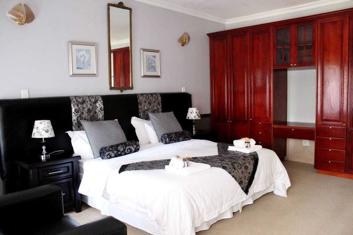 A hotel room with a large bed, two bedside tables, a wardrobe, and a mirror on the wall.